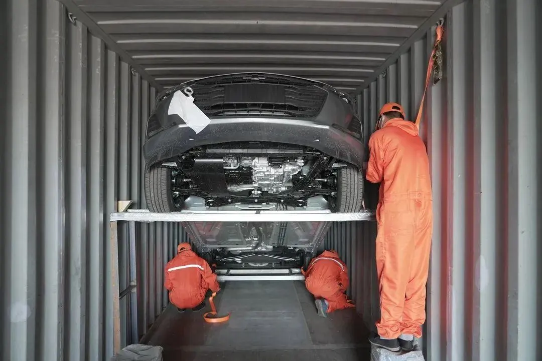 Export cars strapped to racks inside a shipping container